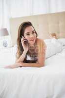 Pretty brunette talking on the phone in bed