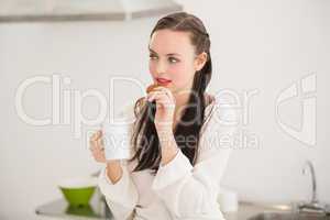 Pretty brunette holding a mug and cookie