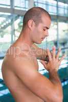 Side view of shirtless fit swimmer by pool at leisure center