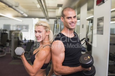 Couple exercising with dumbbells in gym