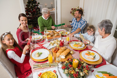 Smiling family pulling christmas crackers at the dinner table