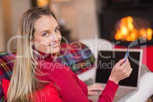 Smiling blonde shopping online with laptop at christmas