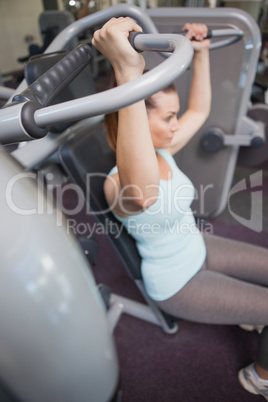 Fit brunette using weights machine for arms