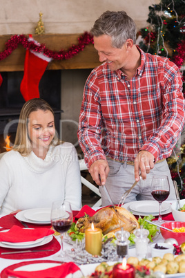 Man carving chicken during christmas dinner
