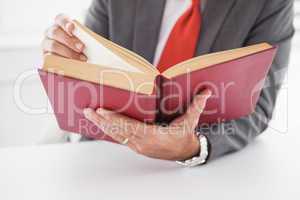 Businessman sitting at desk reading book