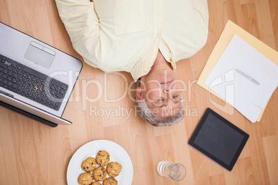 Man lying on floor surrounded by various objects