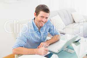 Smiling businessman writing at his desk