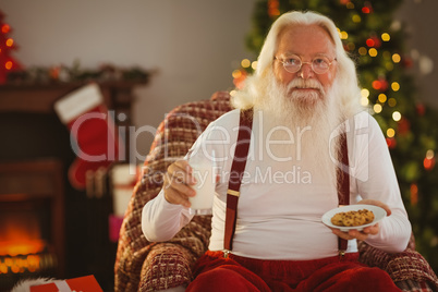 Santa holding glass of milk and plate with cookie