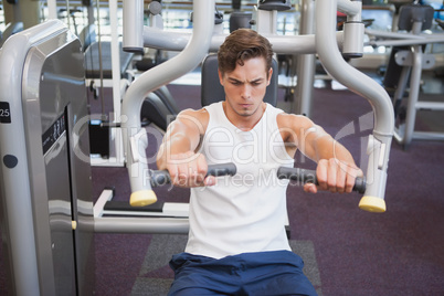 Fit man using weights machine for arms