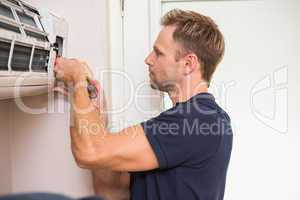 Focused handyman testing air conditioning