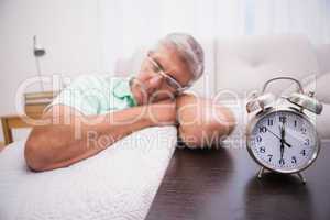 Man dozing on the couch beside alarm clock