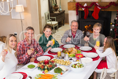 Smiling family toasting to camera during christmas dinner