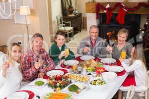 Smiling family toasting to camera during christmas dinner