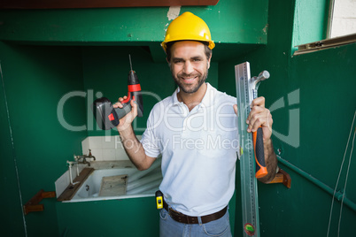 Construction worker holding spirit level and drill