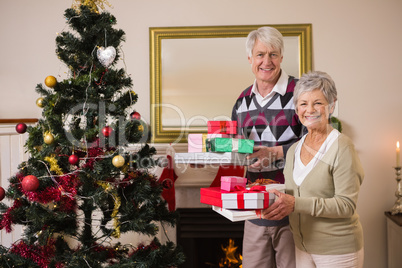Senior couple swapping gifts by their christmas tree