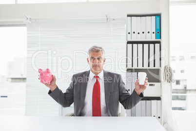 Mature businessman holding coffee and piggy bank