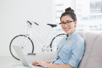 Young creative woman using laptop on couch