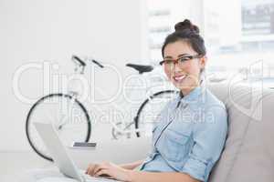 Young creative woman using laptop on couch