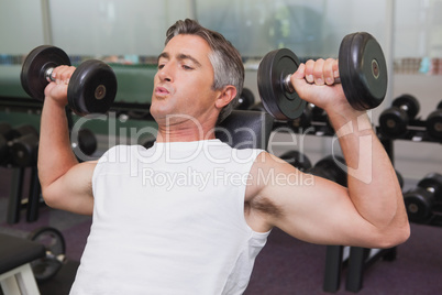 Fit man lifting dumbbells lying on the bench