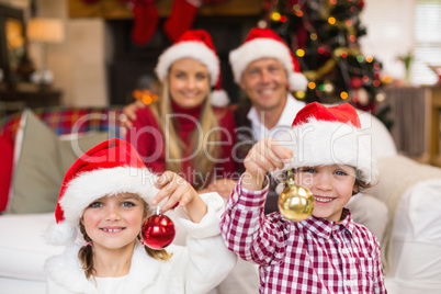 Cute little siblings wearing santa hat holding baubles