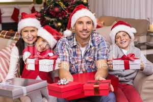 Festive family on the couch offering gifts