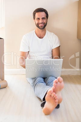 Happy man using laptop surrounded by boxes