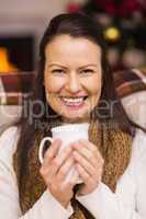 Smiling brunette enjoying a hot drink at christmas