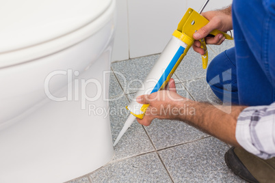 Handyman filling in tiles in bathroom