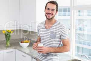 Young man smiling and holding coffee