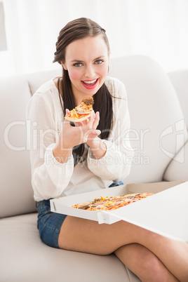 Pretty brunette eating slice of pizza