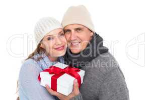 Casual couple in warm clothing holding gift