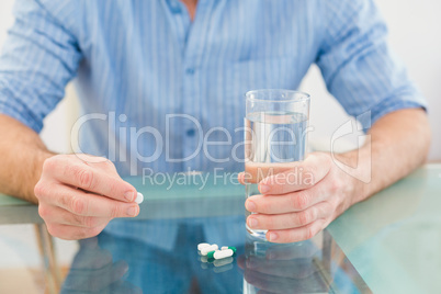 Casual businessman holding glass of water and tablet