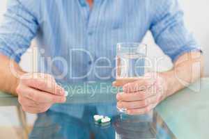 Casual businessman holding glass of water and tablet