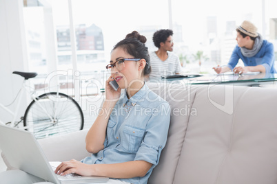 Young creative woman using laptop on couch