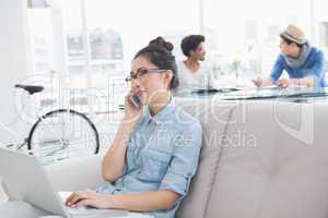 Young creative woman using laptop on couch