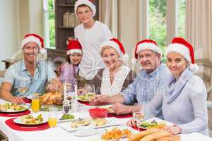 Family in santa hat looking at camera at christmas time