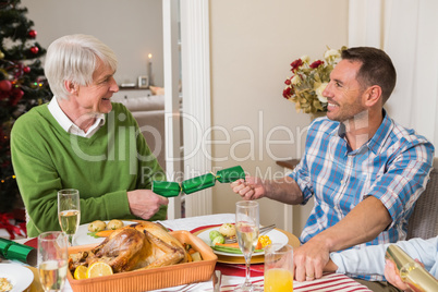 Grandfather and father pulling christmas crackers