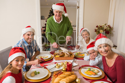 Grandfather in santa hat carving roast turkey at christmas dinne