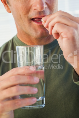 Closeup mid section of a man with glass of water and pill