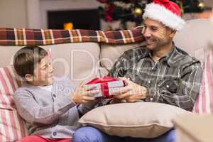 Son giving father a christmas gift on the couch