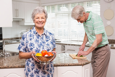 Senior woman showing colander of vegetables Senior woman showing colander of vegetables
