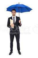 Serious businessman holding a file under umbrella
