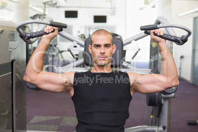 Serious man working on fitness machine at gym