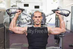 Serious man working on fitness machine at gym