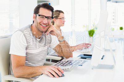 Man wearing glasses sitting at desk looking at camera