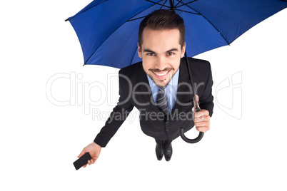 Smiling businessman under umbrella holding smartphone