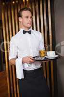 Smiling waiter holding tray with coffee cup and pint of beer