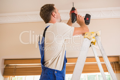 Handyman using a cordless drill to the ceiling