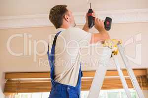 Handyman using a cordless drill to the ceiling