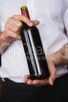 Handsome waiter holding a bottle of red wine